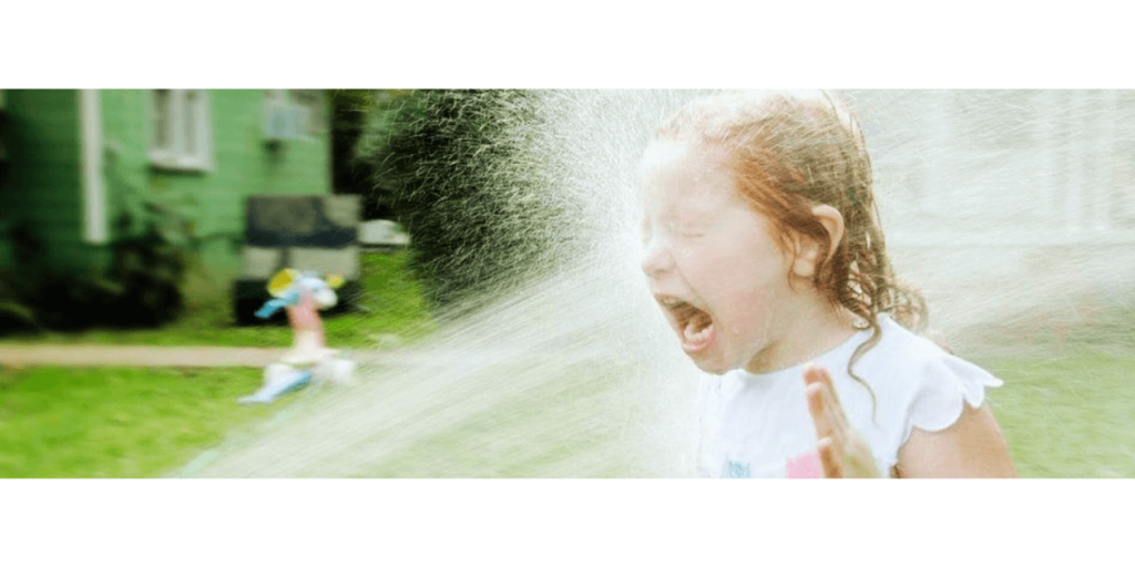little girl struggling to drink water from the hose